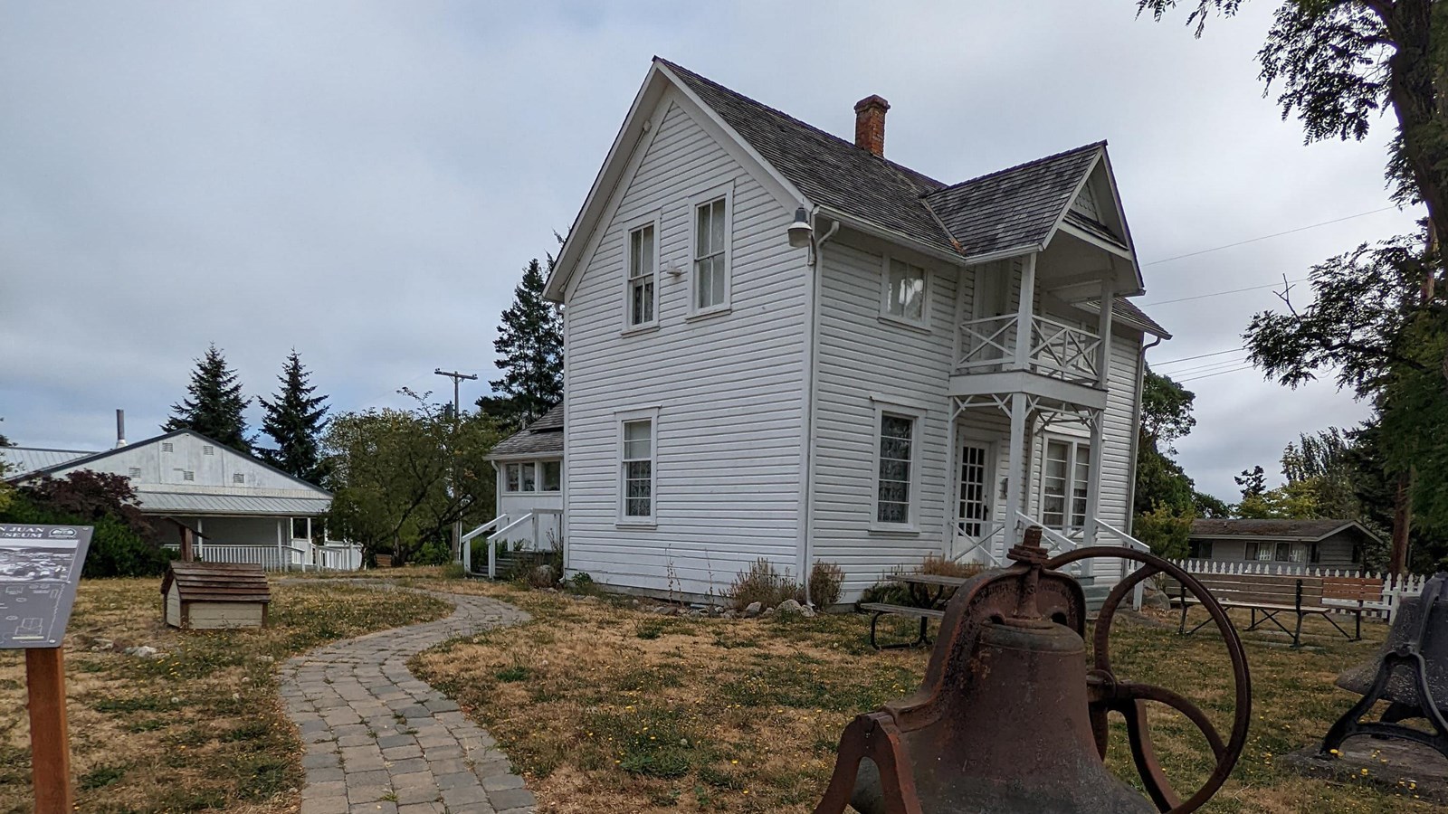 a nineteenth century white wooden building with numerous outbuildings nearby