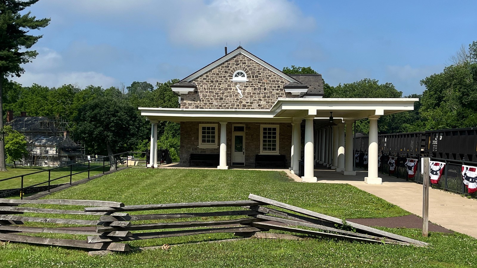 stone building with with columns and a train platform. fence covered in red white blue bunting
