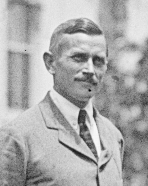 Black and white image of a man wearing a coat and tie.