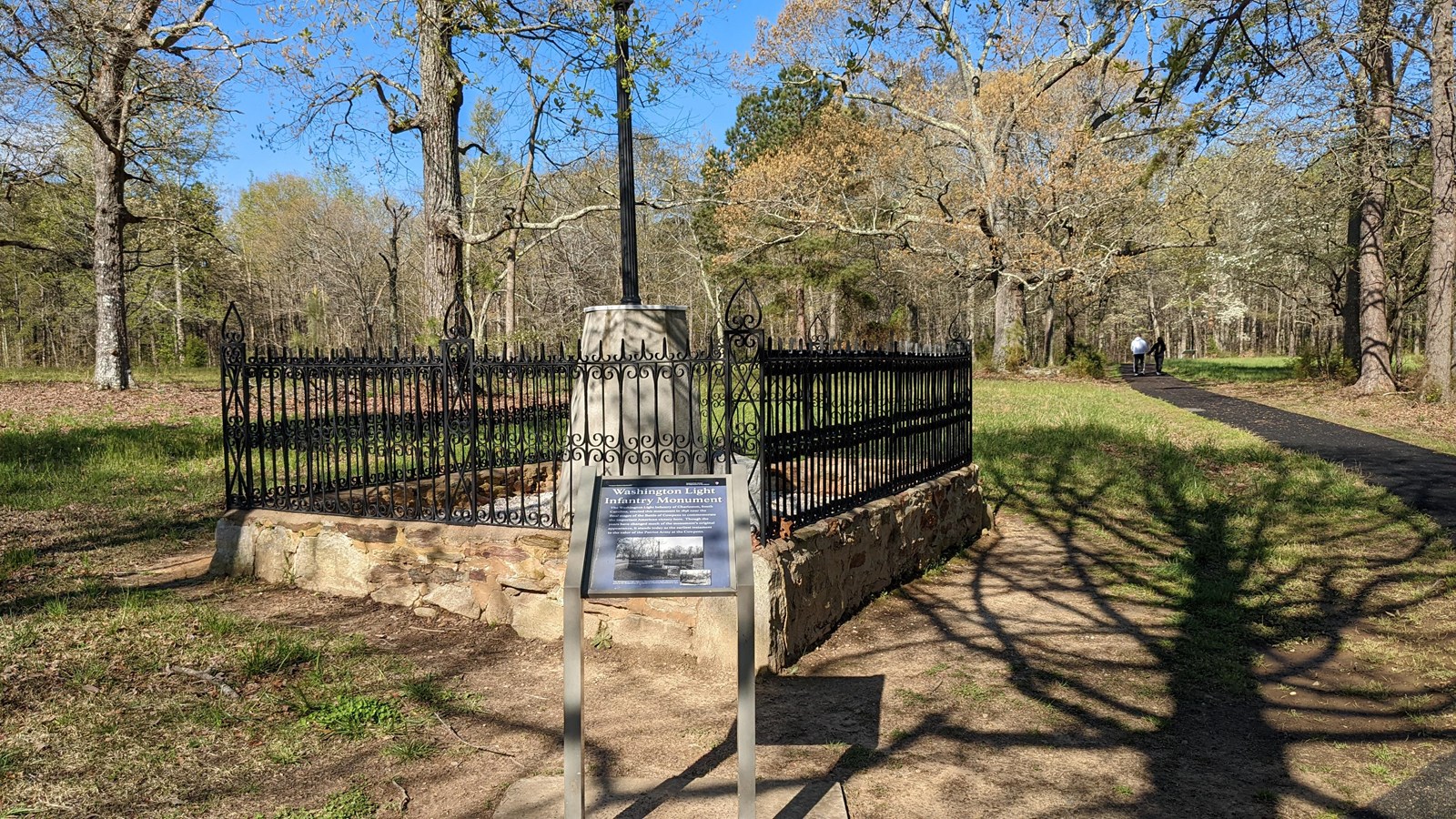 Washington Light Infantry Monument surrounded by a low stone wall and fence on top of the stone wall