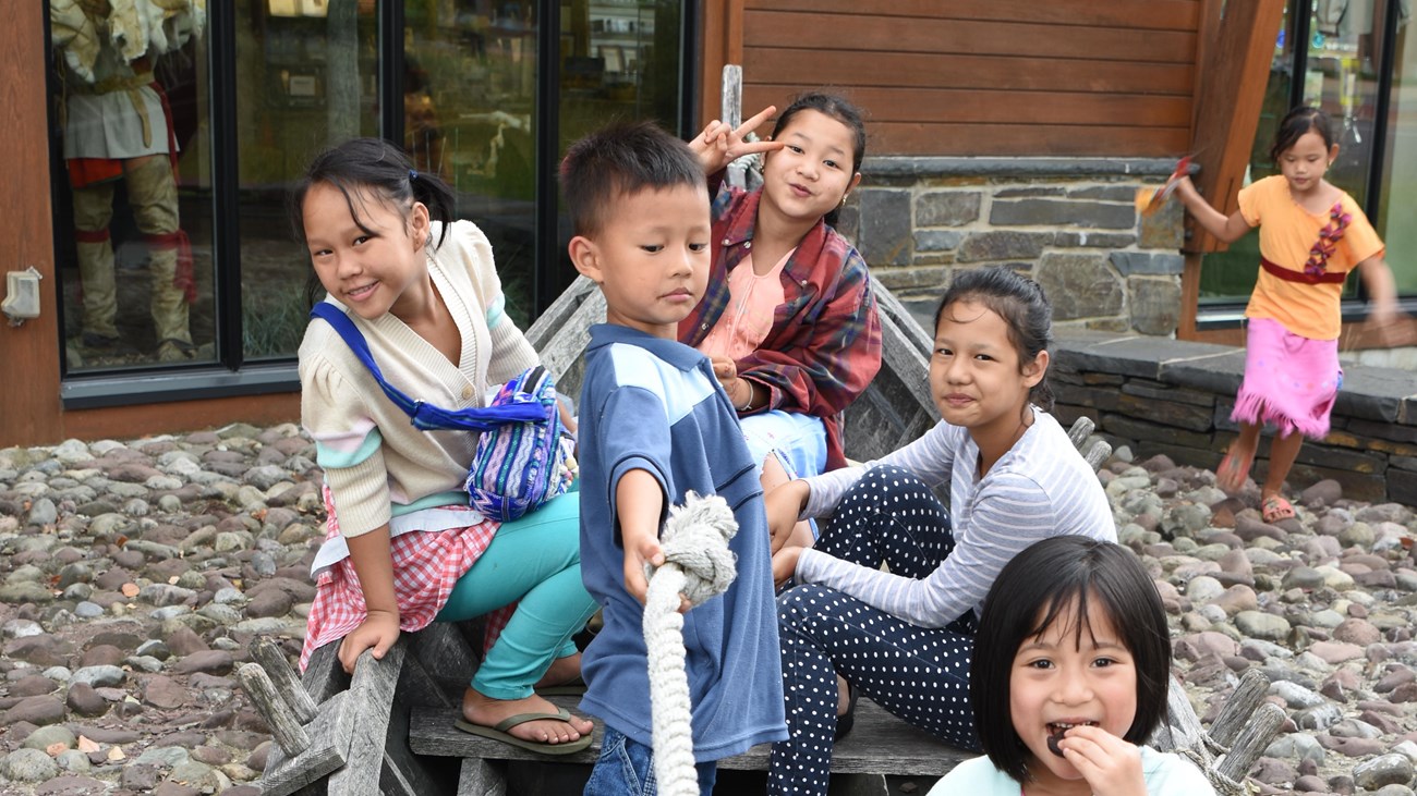 Several kids sit crowded together in a bateau-style boat. 