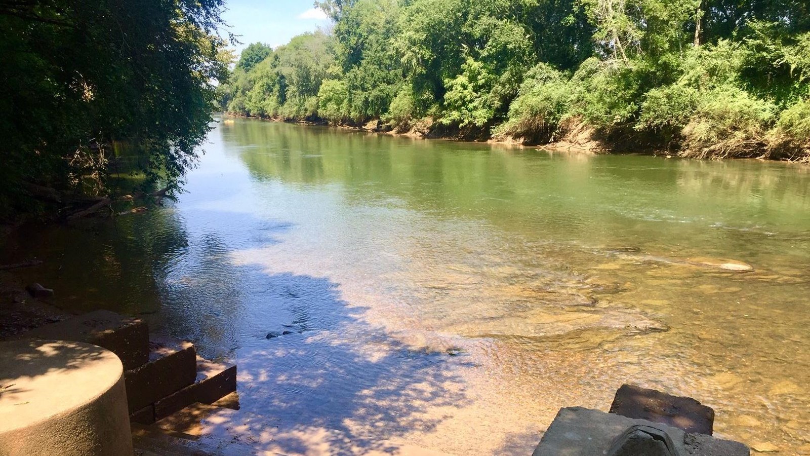 View of the river with end of launch in the foreground and wooded shoreline.