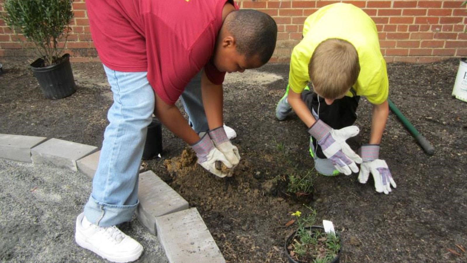 Two kids planting in a garden. 