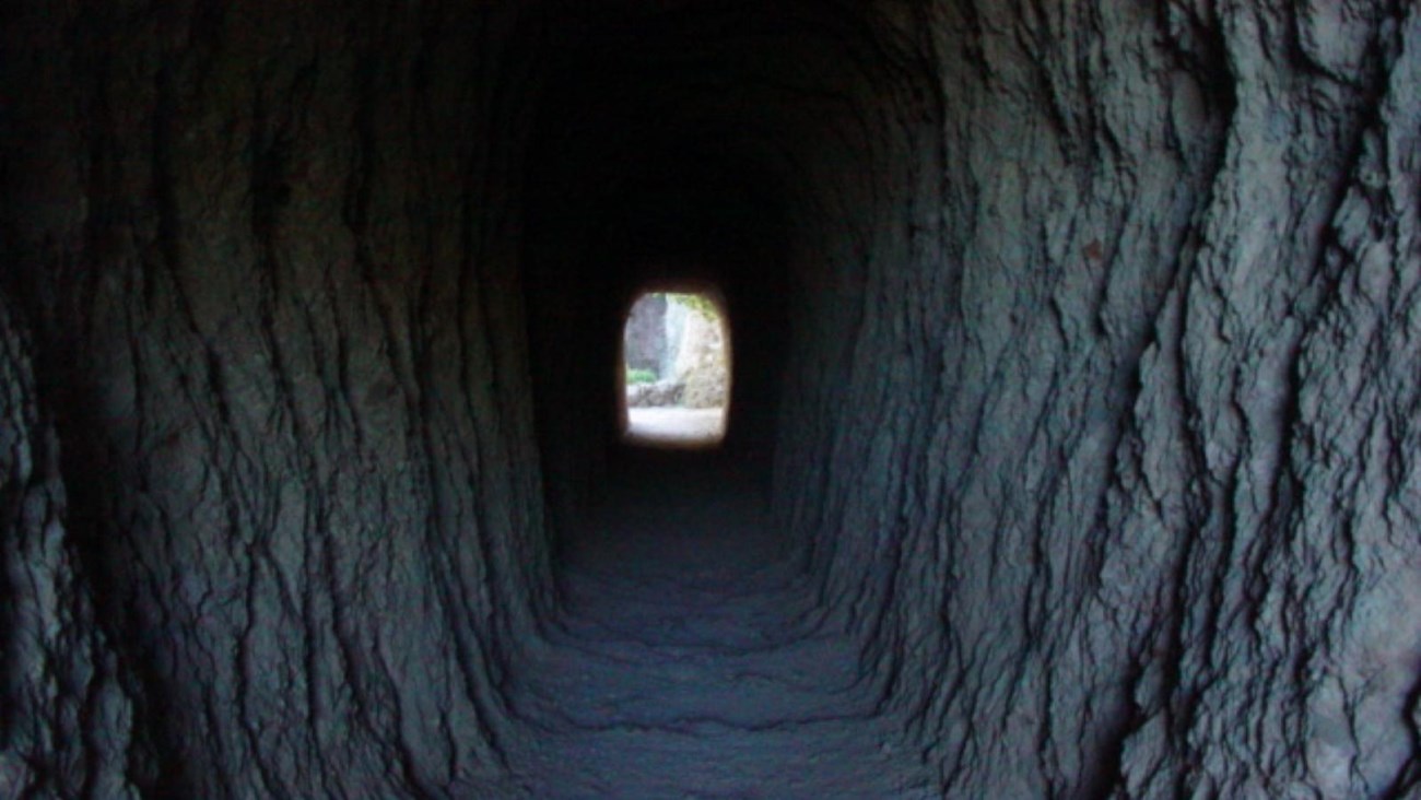 Natural light luminating the walls inside a manmade rock tunnel 