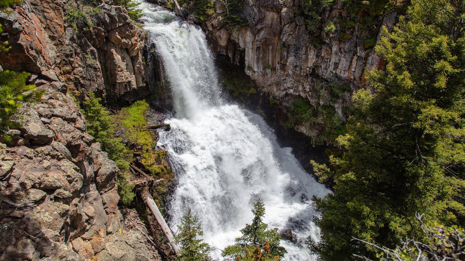 A waterfall descends down three plunges through a rocky gorge.