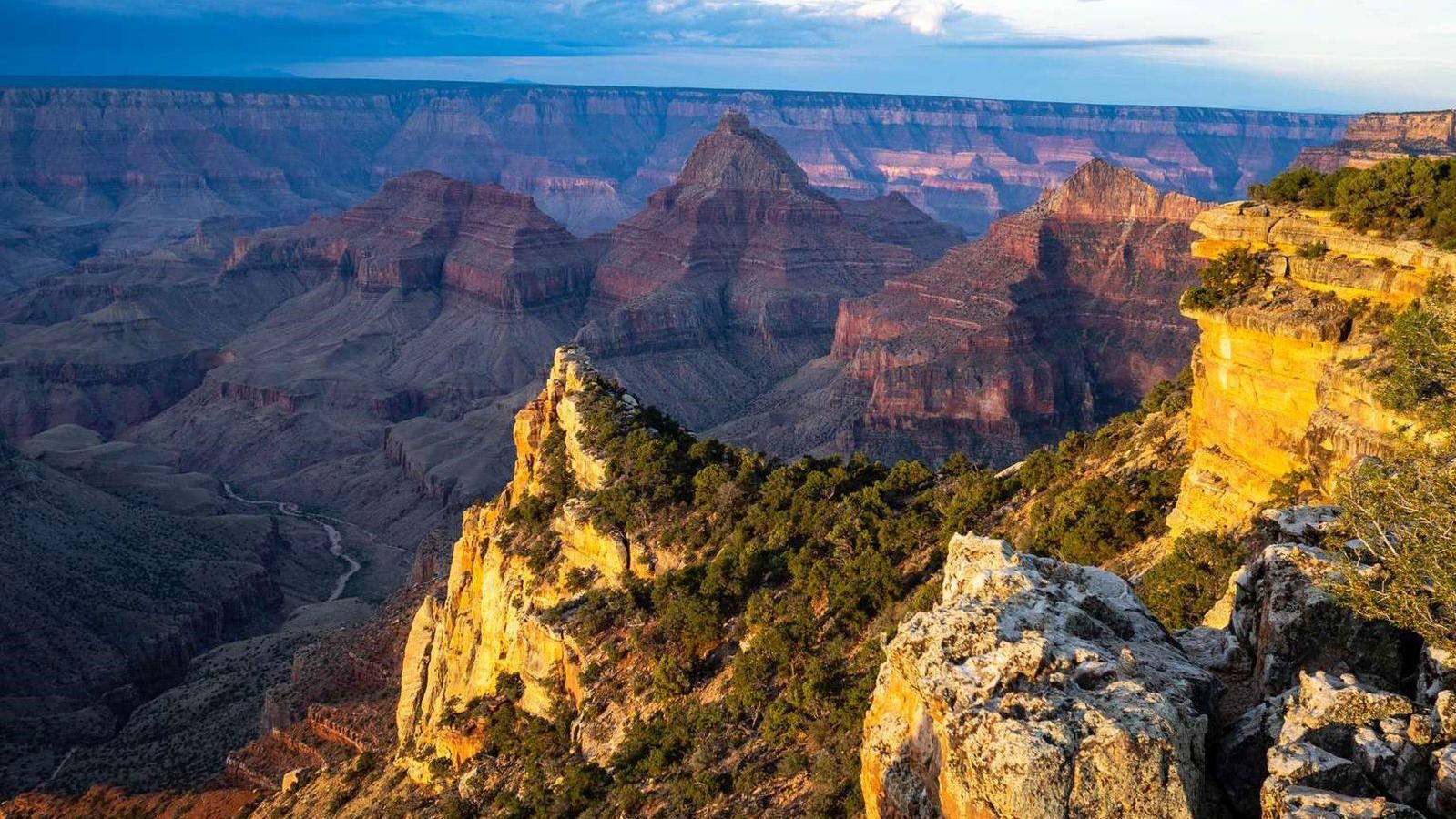 A soft golden light shines on nearby rock formations and cliffs during sunrise at the point.