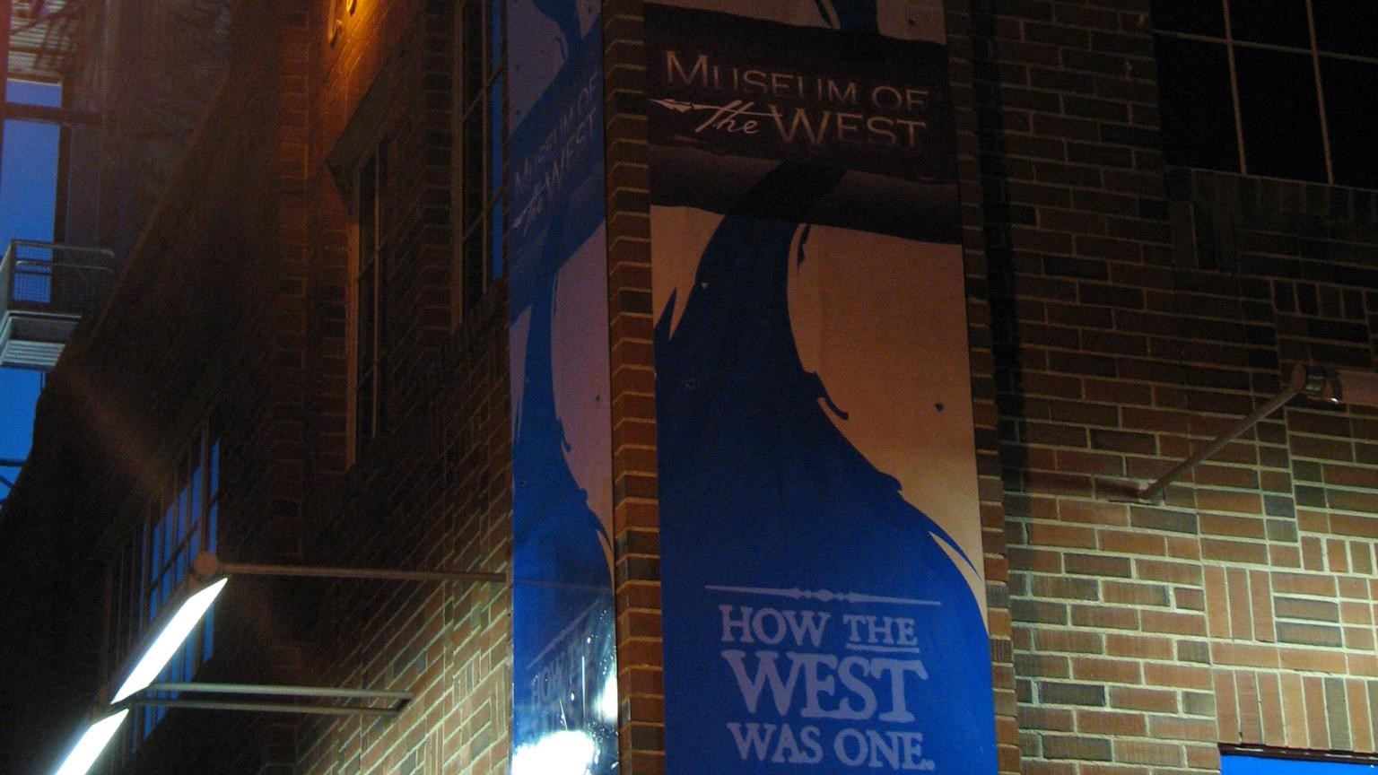 Building at night, the outside The Museum of the West lit by one light from the top right side