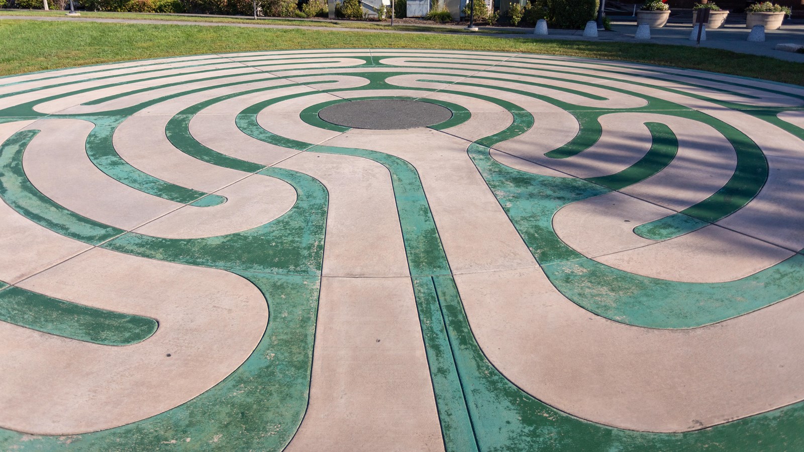 A paved, spiraling maze pattern on a grass lawn.