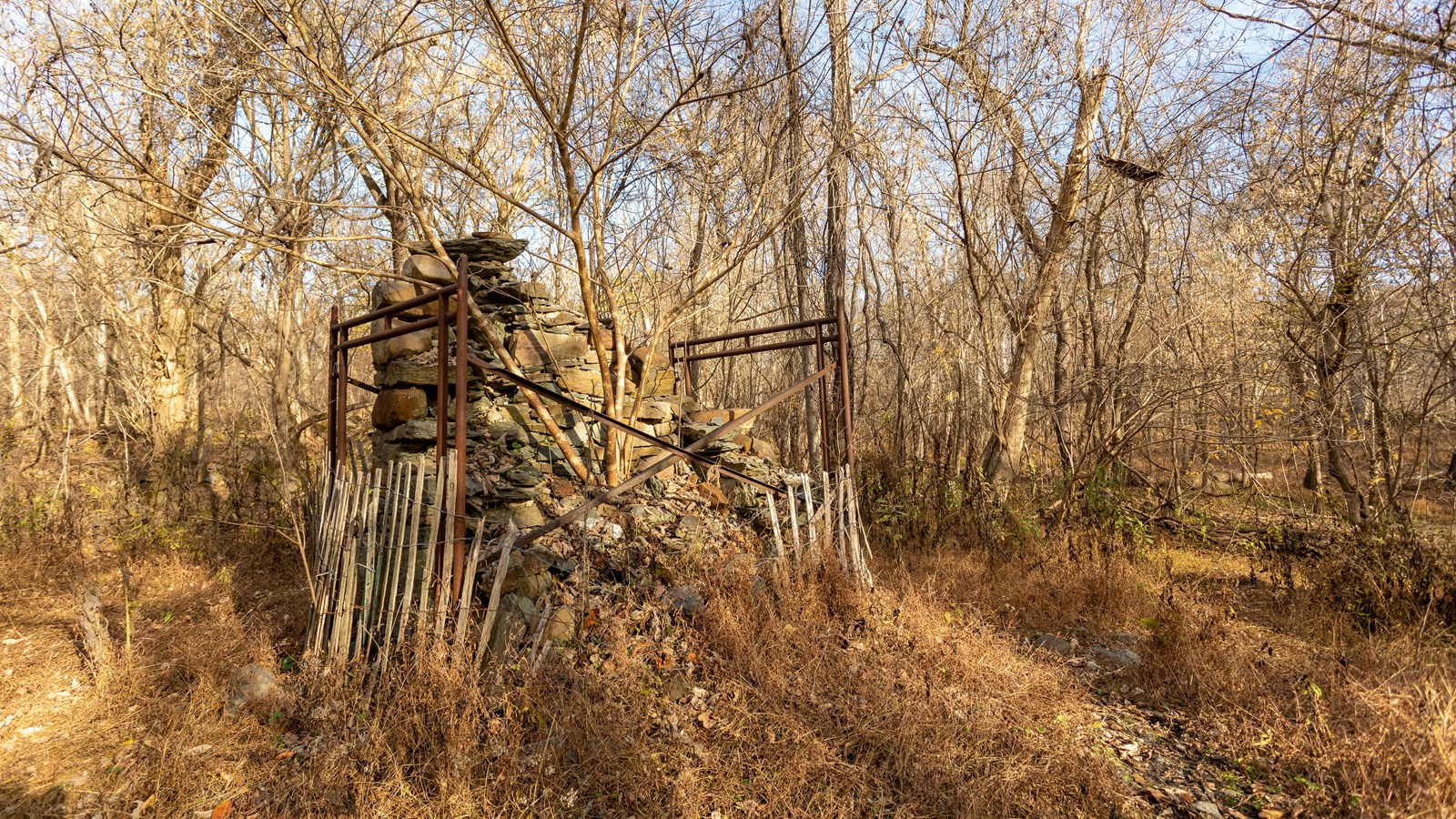 A small stone structure is held together with cement. Metal railings act as a barrier to protect it.