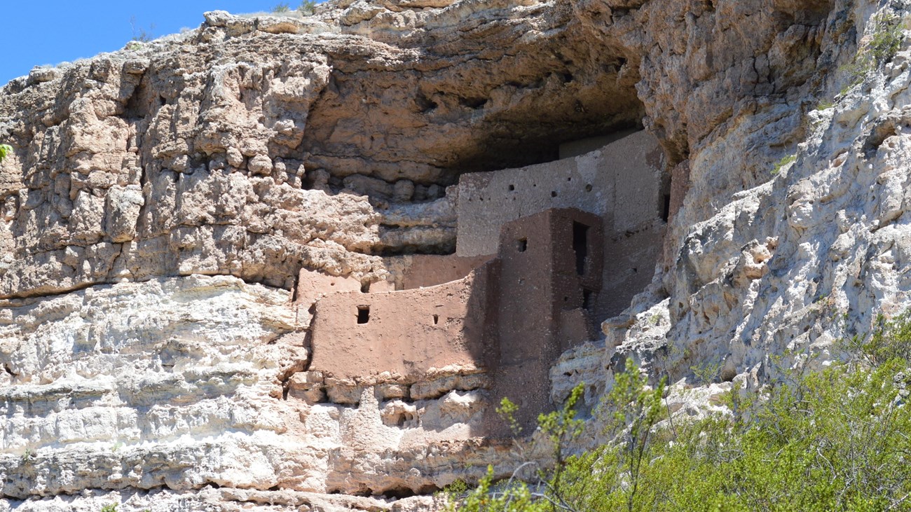 a large cliff dwelling with several visible stories inside a large alcove on the side of a cliff