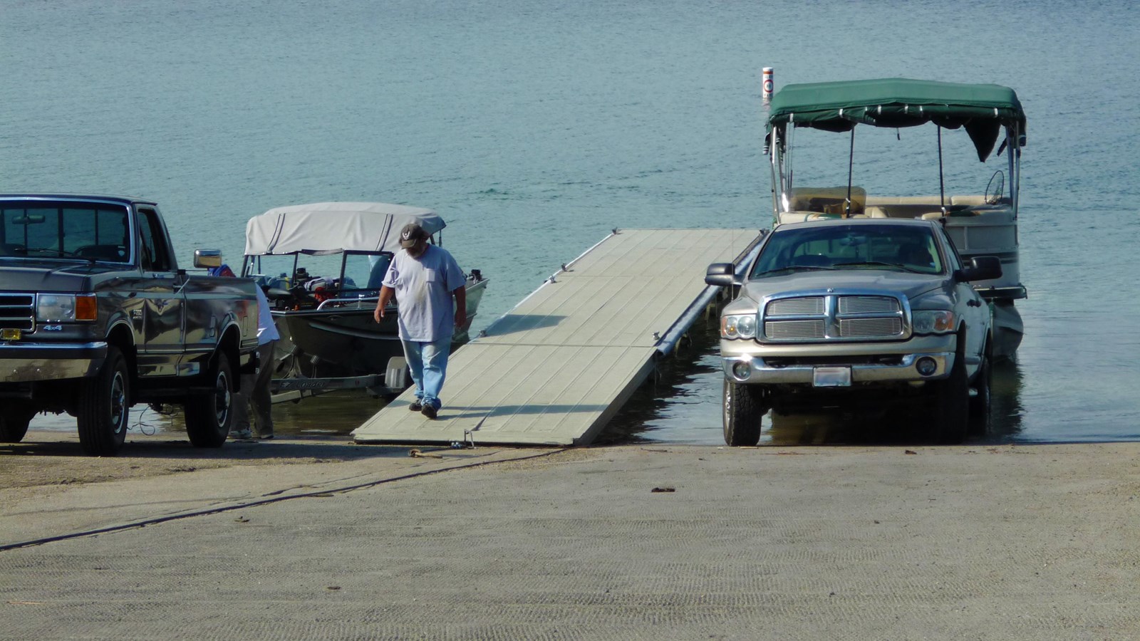 Two trucks with trailers at a paved boat launch.