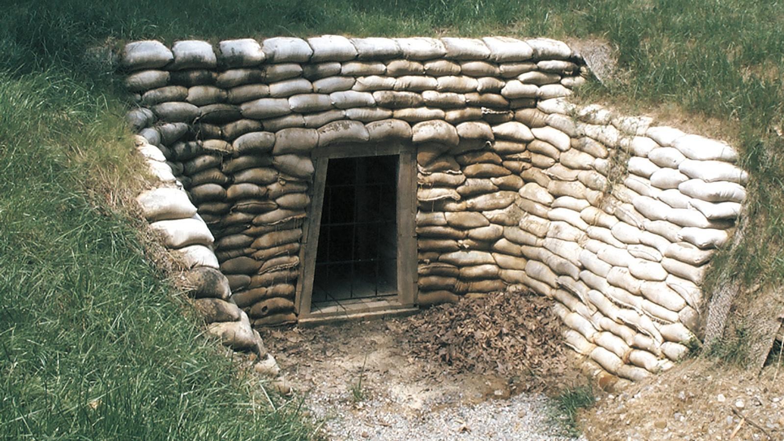 A rectangular doorway into a hillside, surrounded by white cement 