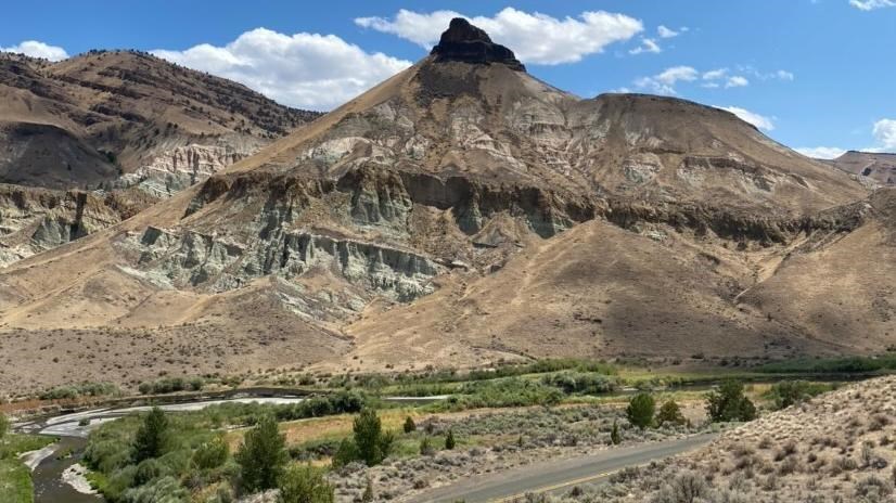 A tall pointed formation with fields and a road in front of it