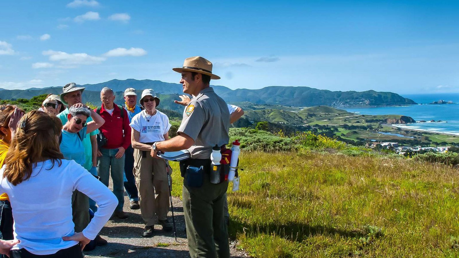 Visitors listen to a ranger along the trail on Milagra Ridge with the ocean visible in the distance.
