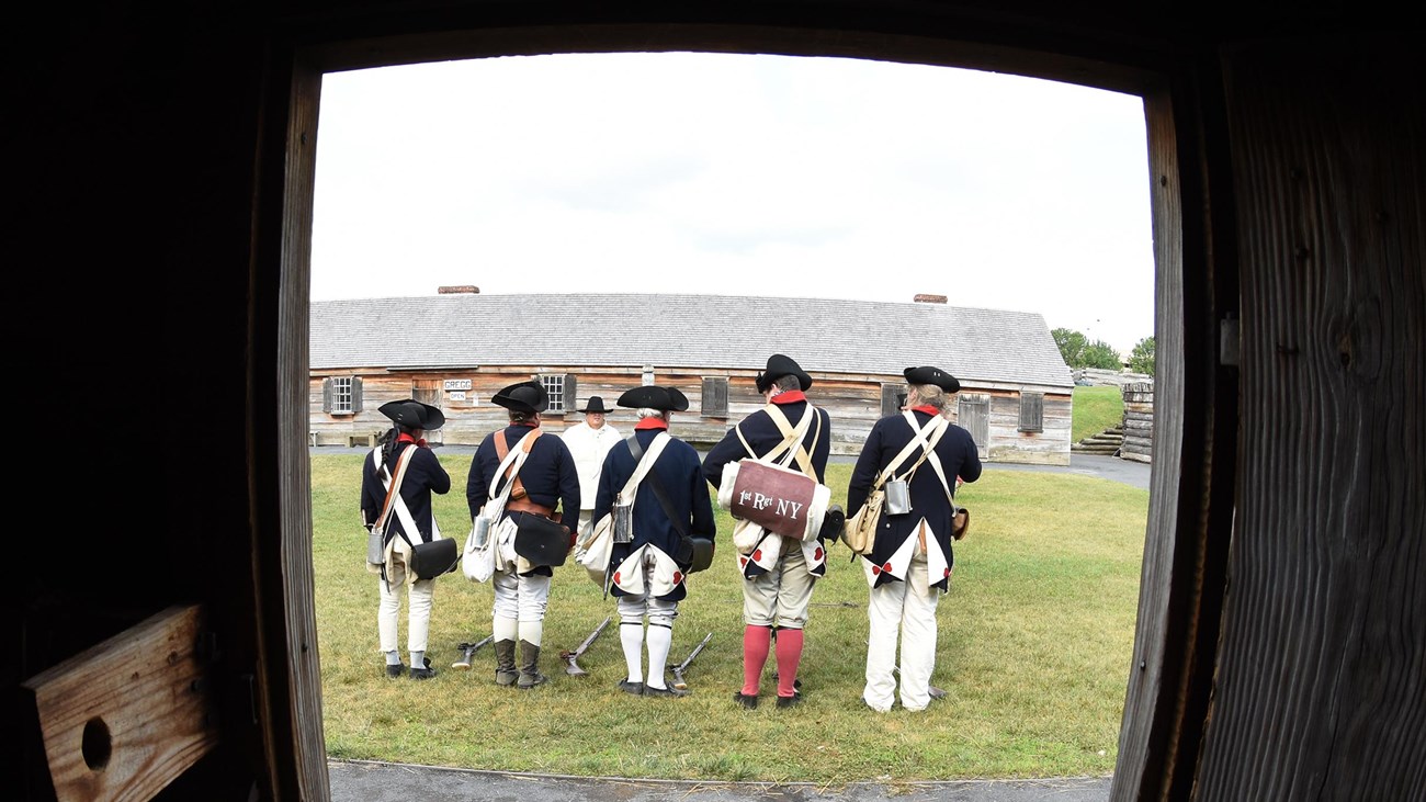 Out of a doorway, you can see several Continental soldiers standing in a line, facing away from you.