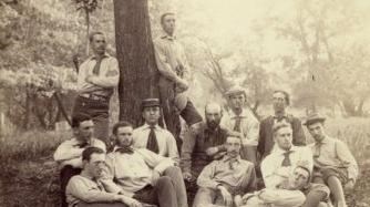 a group of young men pose in front of a tree