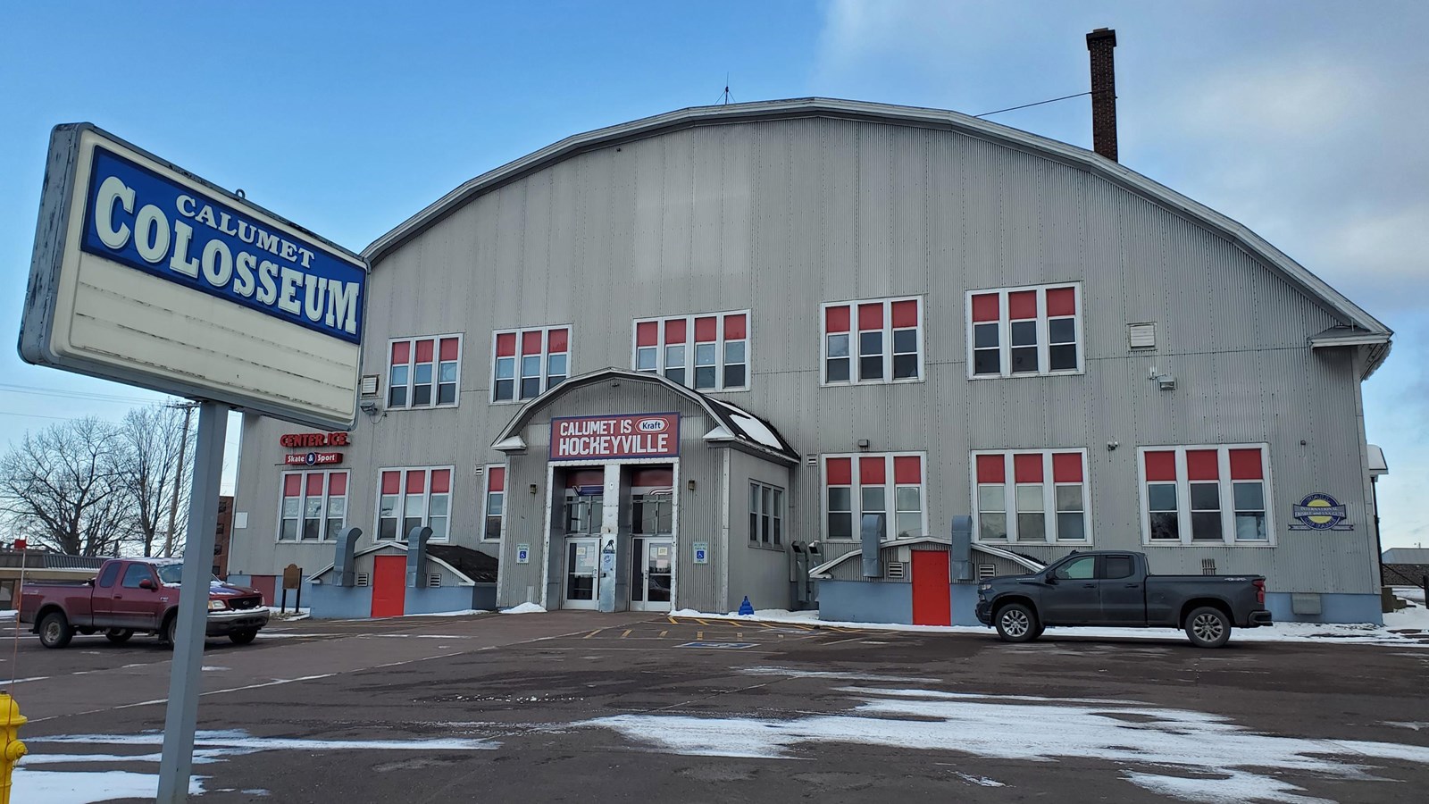 Winter scene of silver colored corrugated metal building with arched roof.