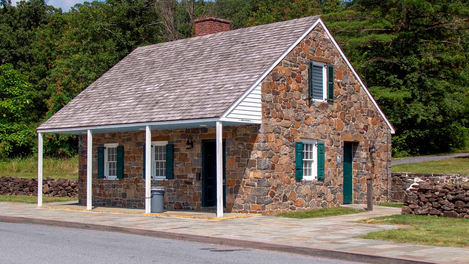 A-frame brown brick building with overhanging roof creating shade in front.