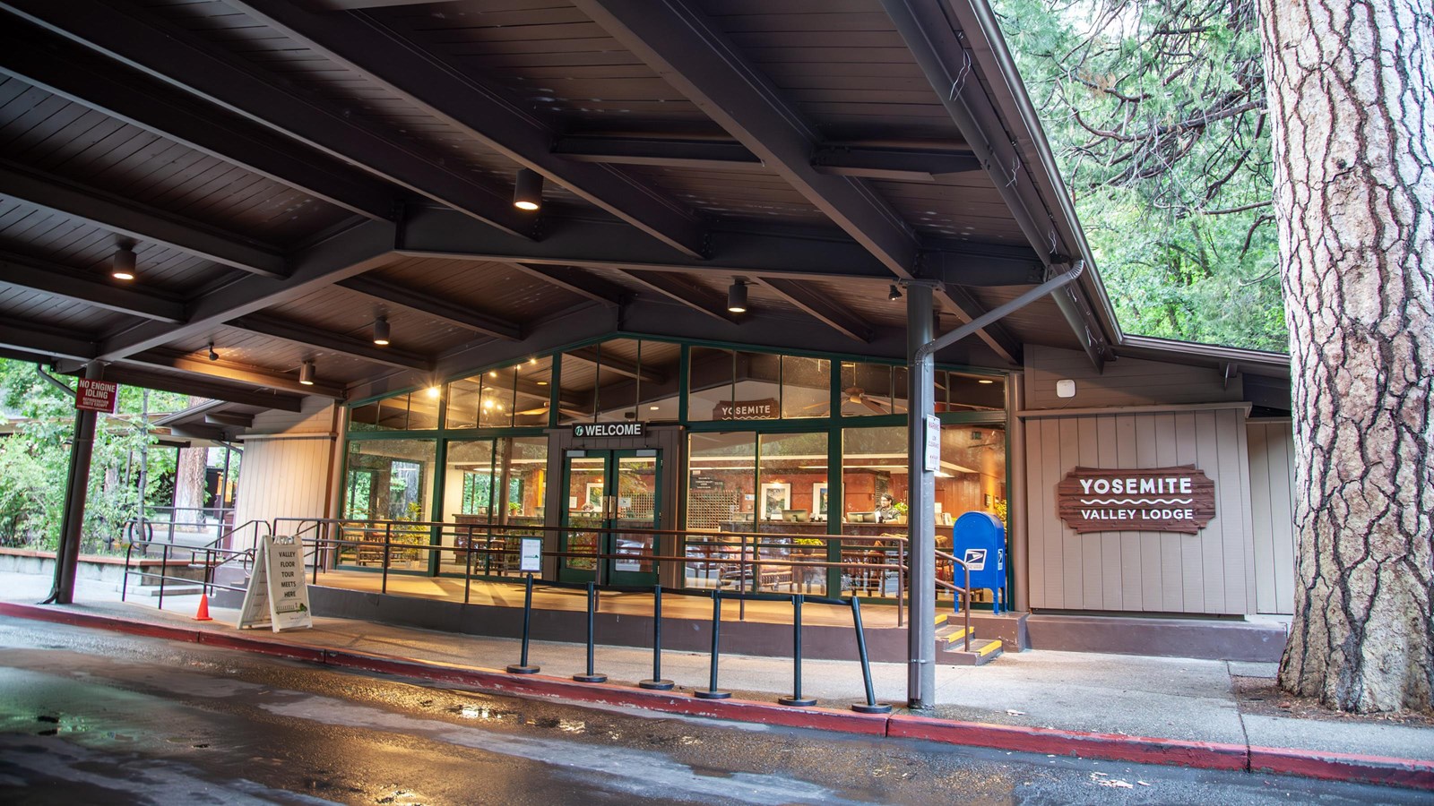 A road leads to a lit building with many windows and a covered entryway