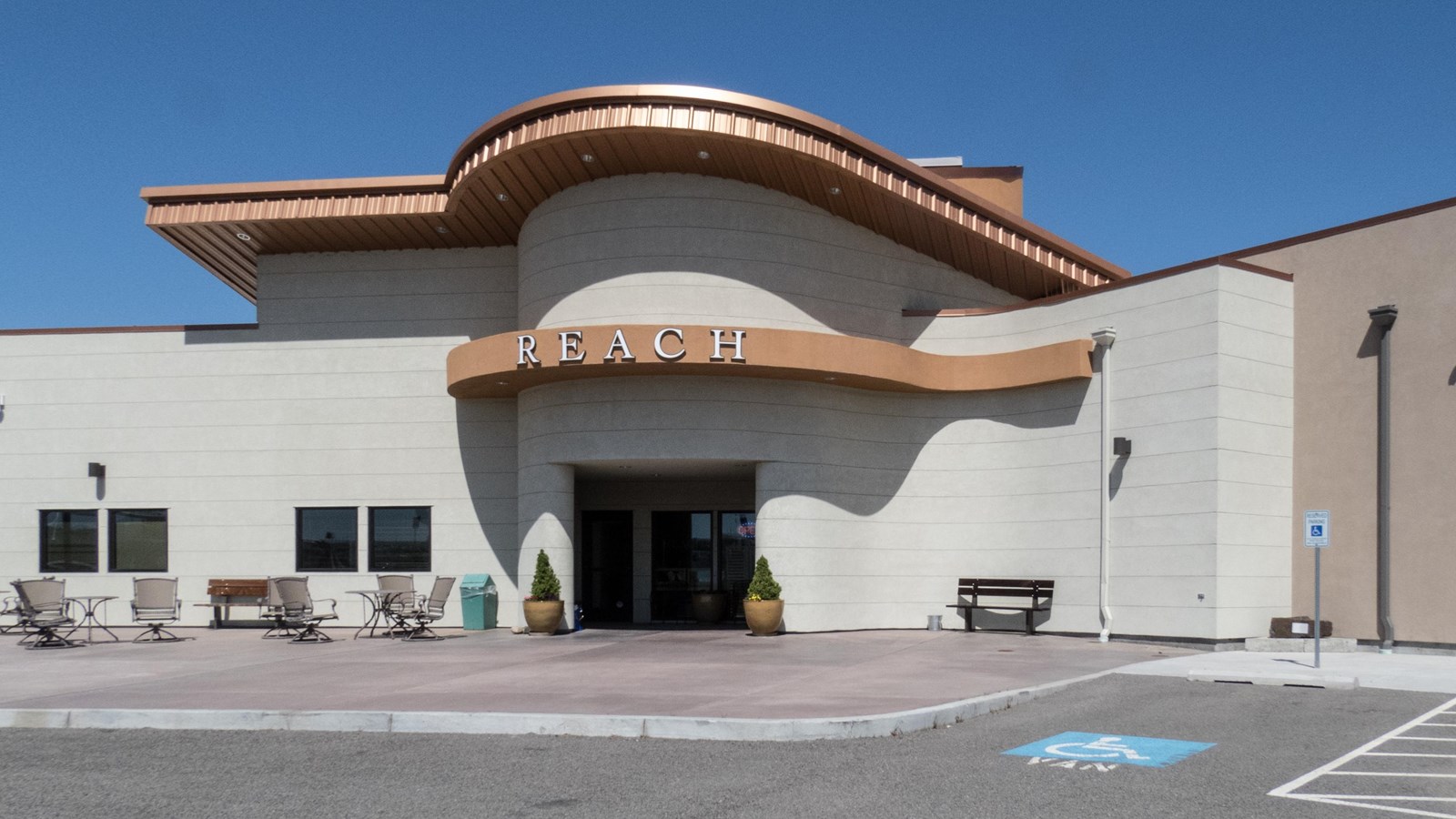 Color photograph of the entrance to a building composed of concrete blocks with a copper roof