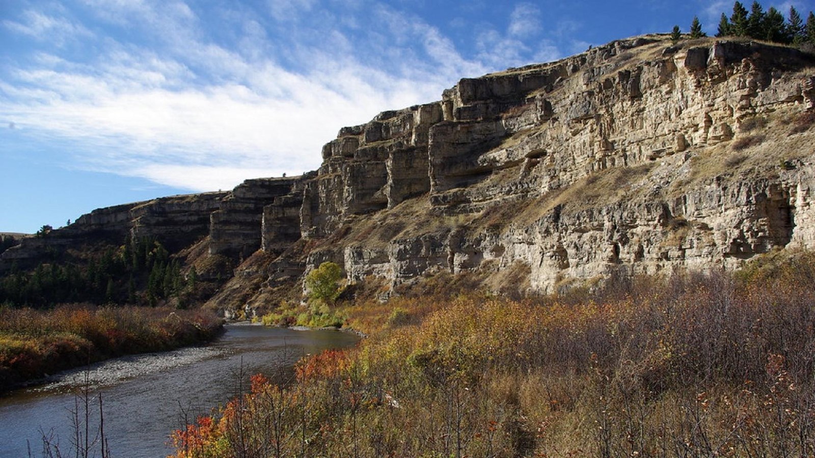 A river winds past sheer limestone cliffs and grassy shoreline. 