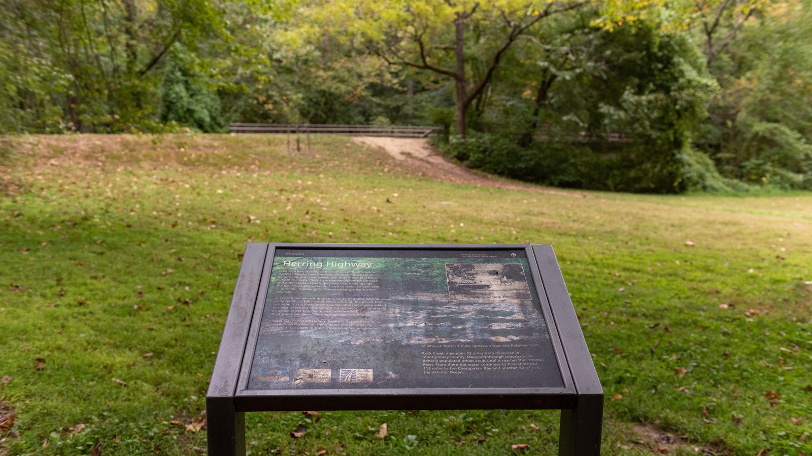 An informational panel in front of a grassy field