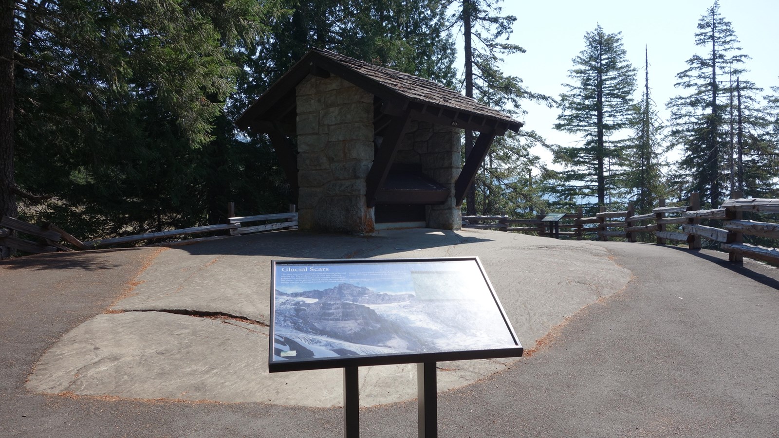 A wayside exhibit in front of a patch of exposed bedrock with a historic exhibit kiosk built on top.