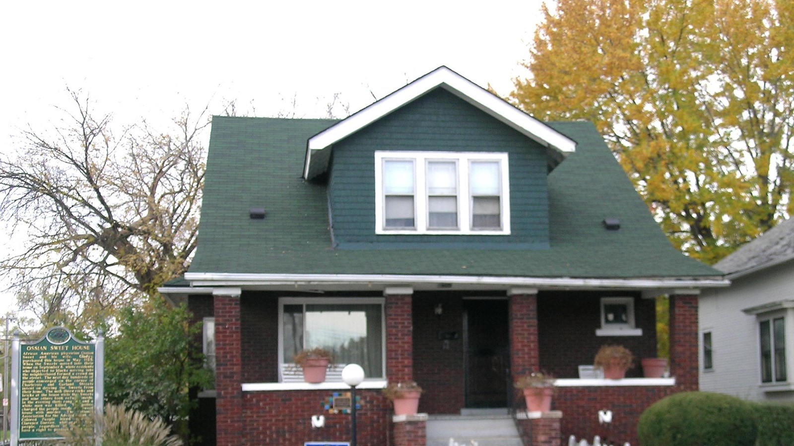 Photo of two-story brick house and white fence. 