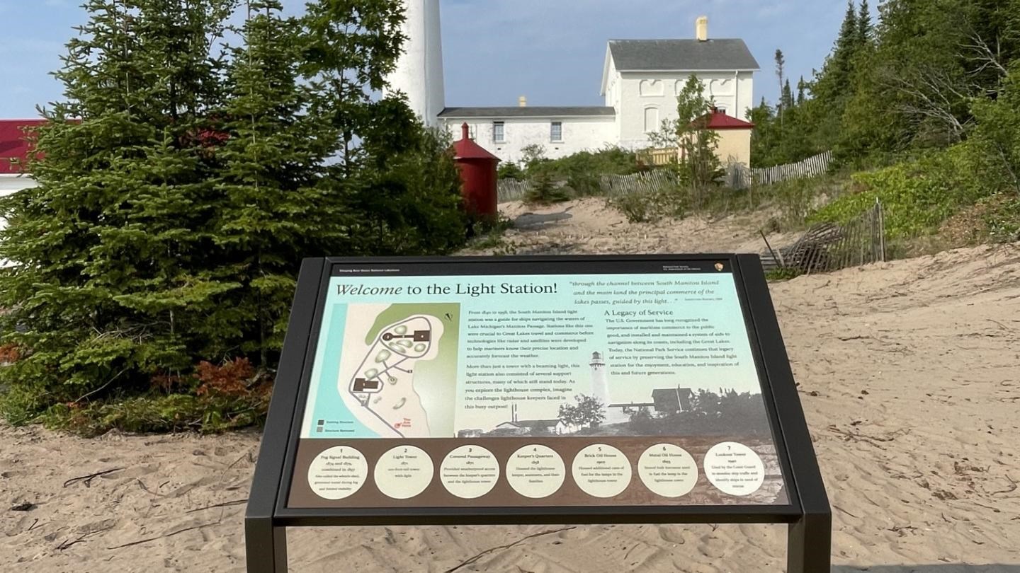 a cantalever wayside attached to a wooden platform. A  white lighthouse stands in the distance