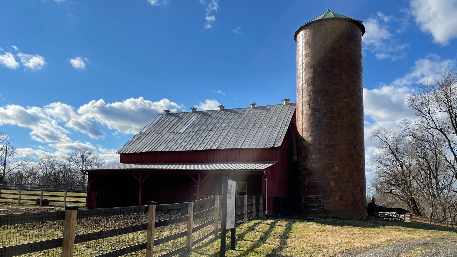 A tall tiled silo on the side of a red barn