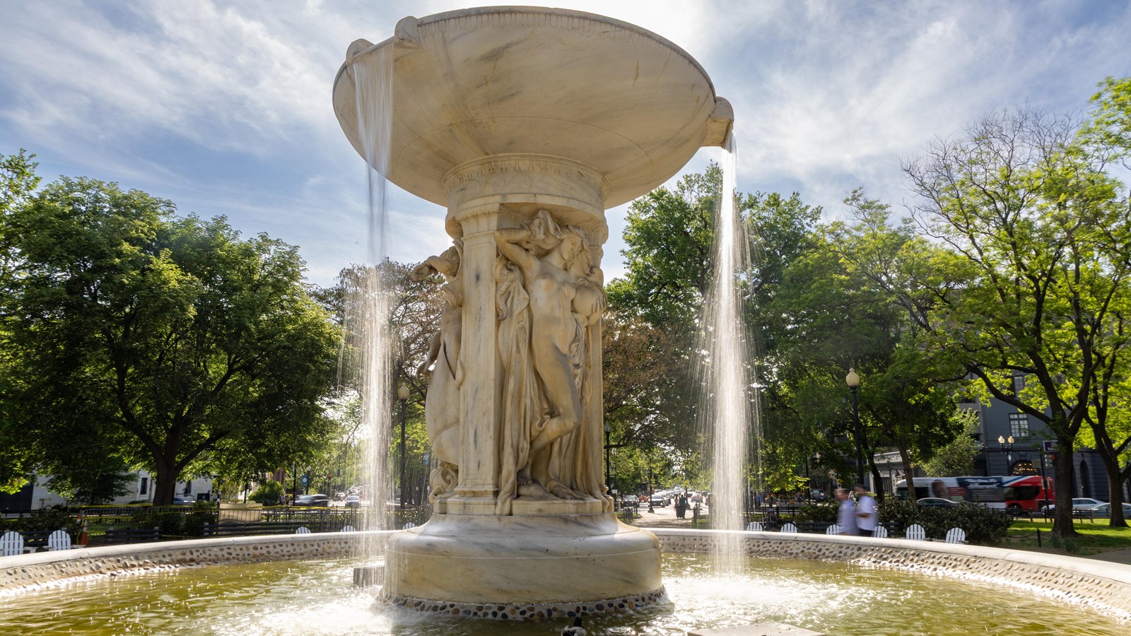 A marble fountain with a large basin on top spills water over the top.