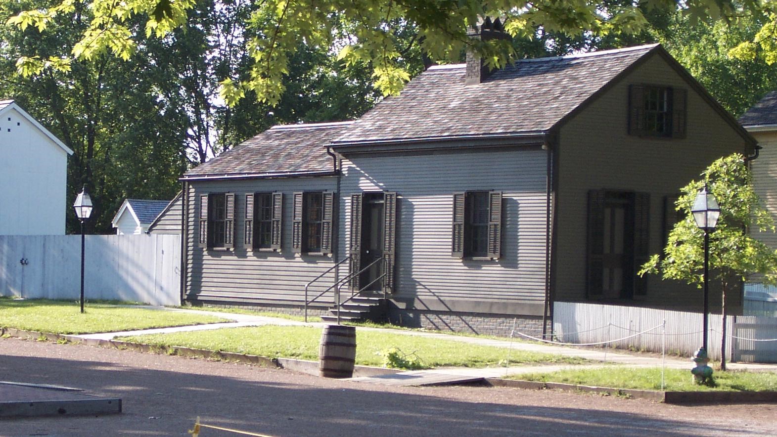 1 story small wood house, light gray with dark gray trim. 