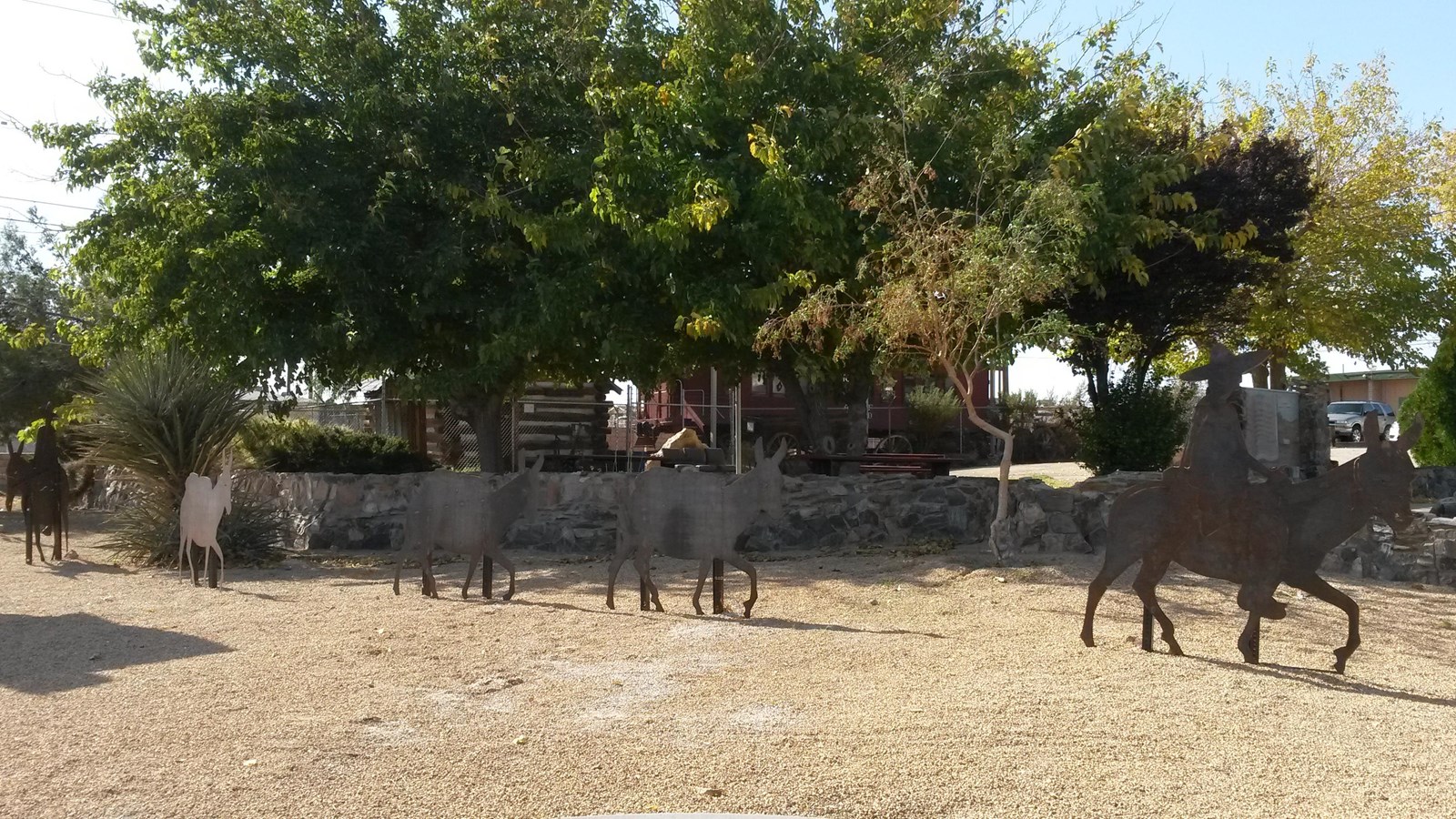 Silhouettes of people on horseback in front of trees.
