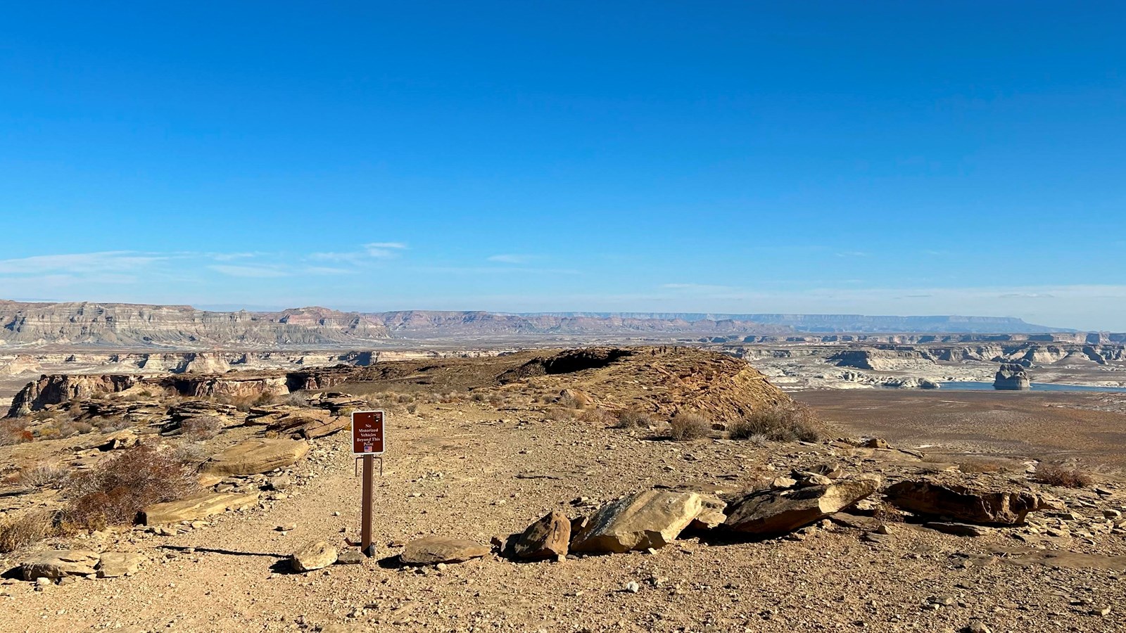 Small brown sign blocking vehicles from a footpath on top of a cliff