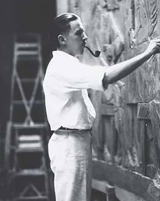 man with a pipe in his mouth holding a tool and sculpting a stone bas-relief