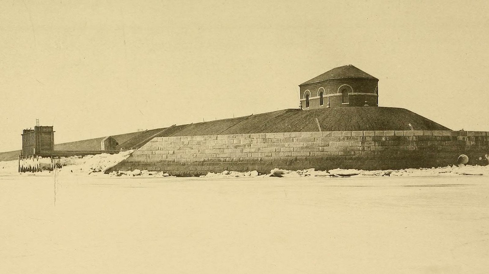 Black and White Photo of a brick pumping station located on the edge of the harbor