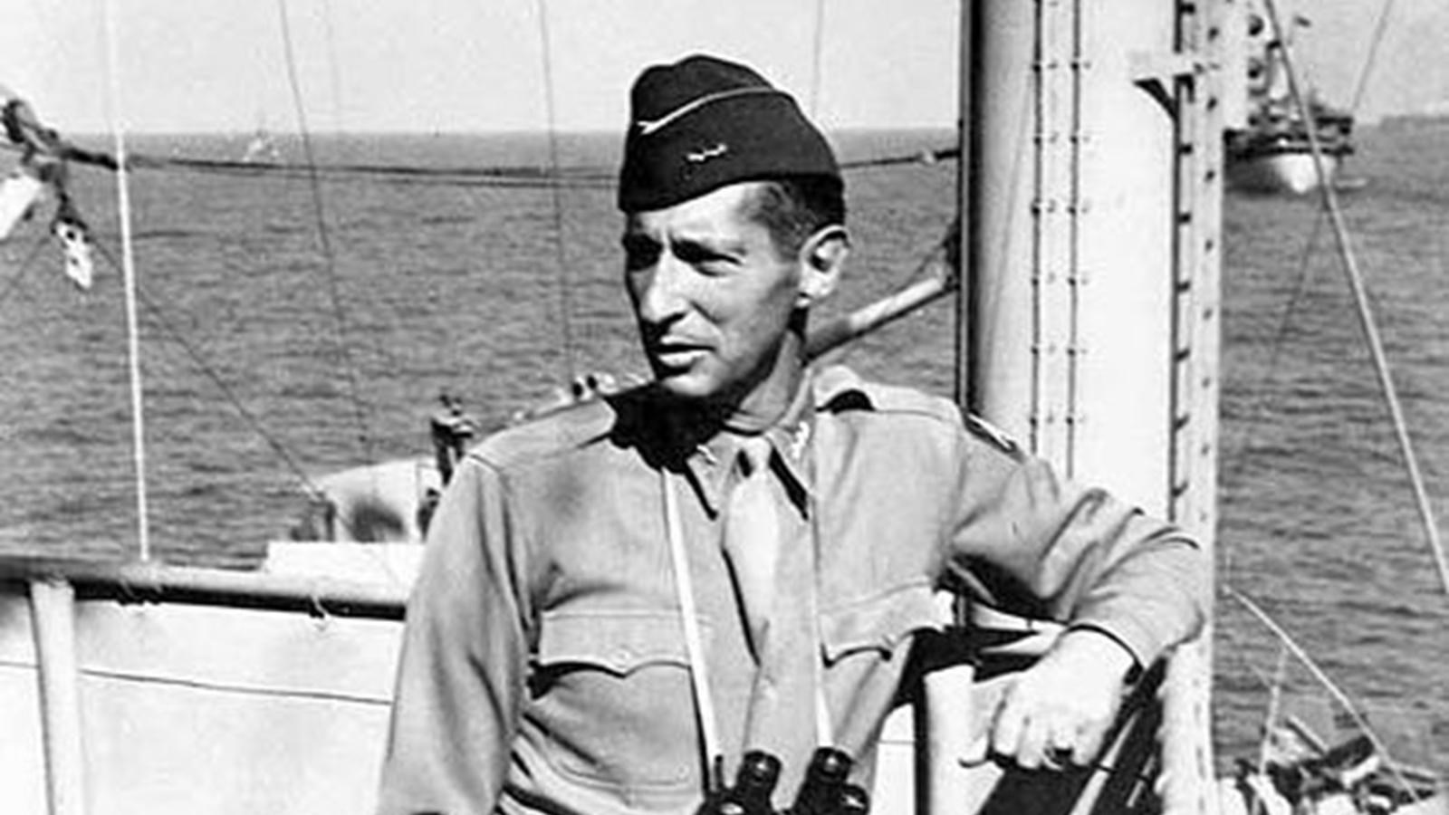 Men in uniform stand on a boat with binoculars around neck.