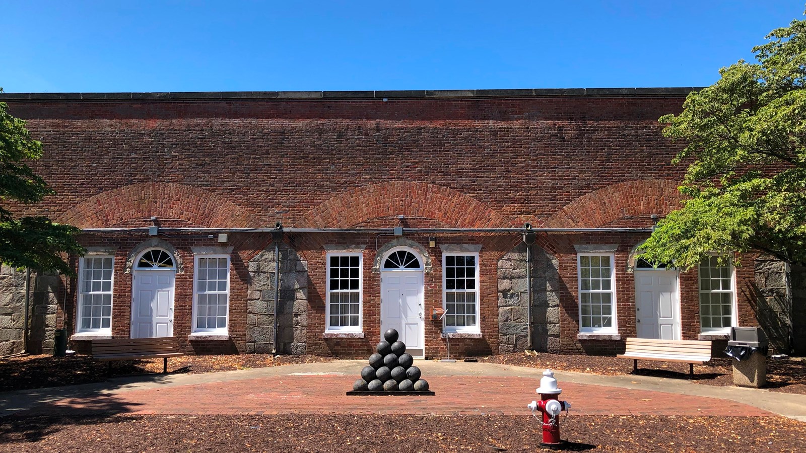 Casemate Museum Entrance centered in a series of casemates with stacked cannon under blue sky balls 
