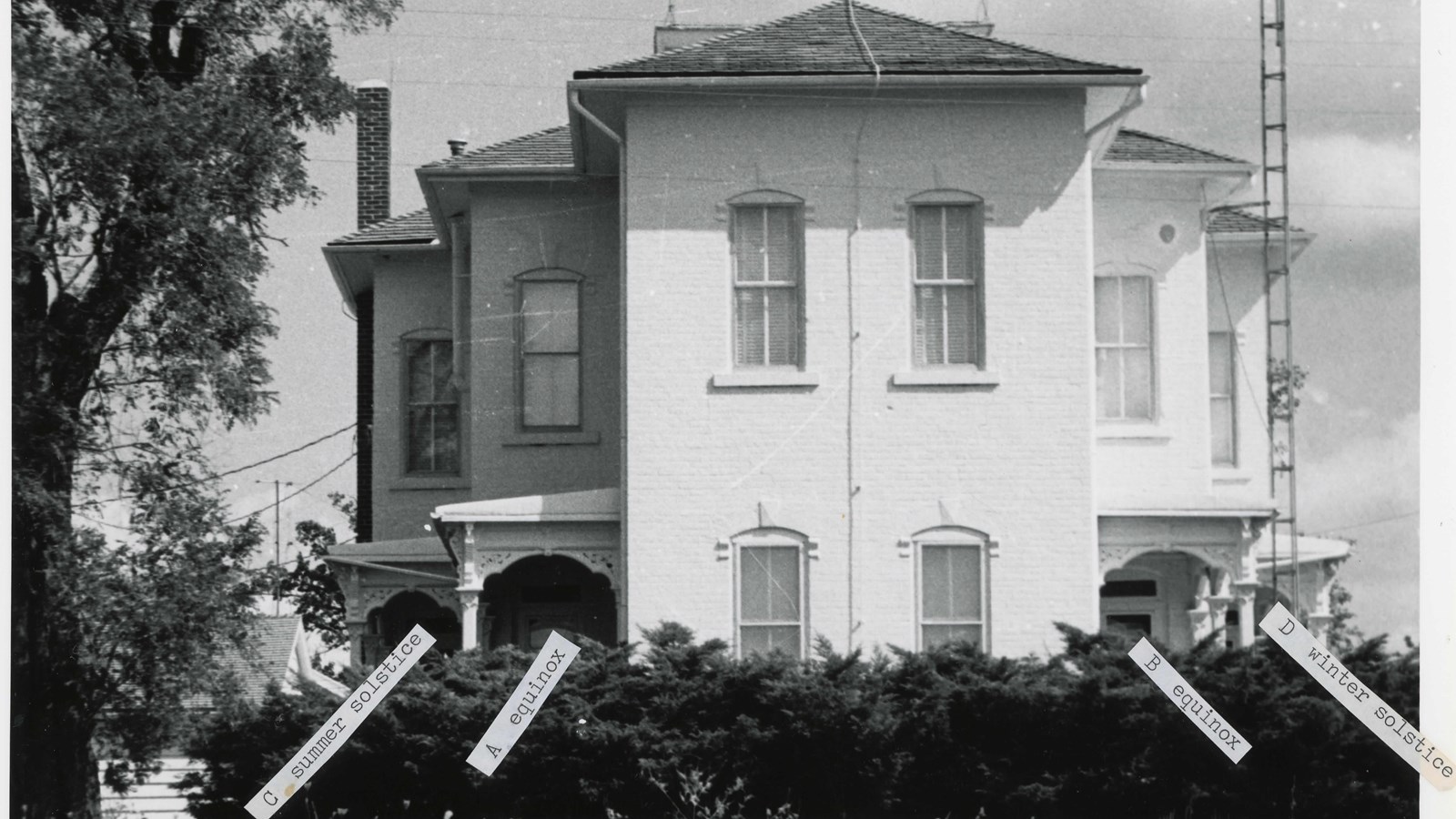 Two story white house with tags noting the solstices and equinoxes