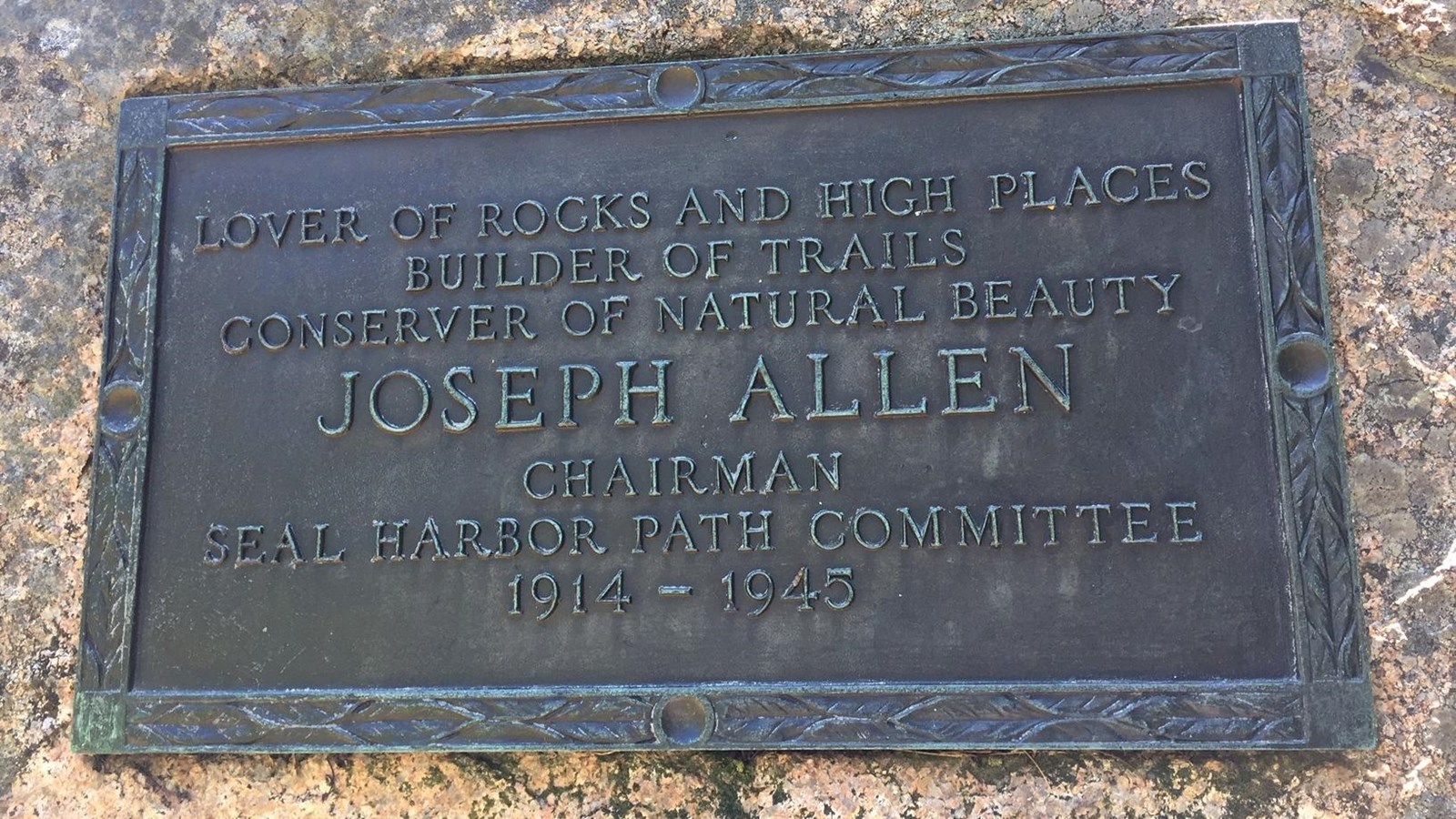 Bronze rectangular plaque with intricate border on granite