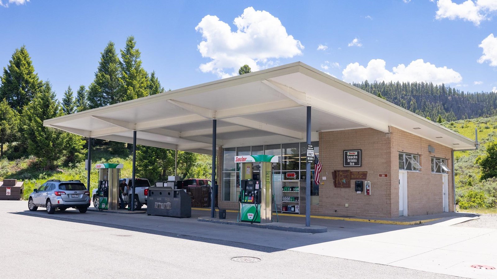 Square brick building with glass front and canopy over the gas pumps.