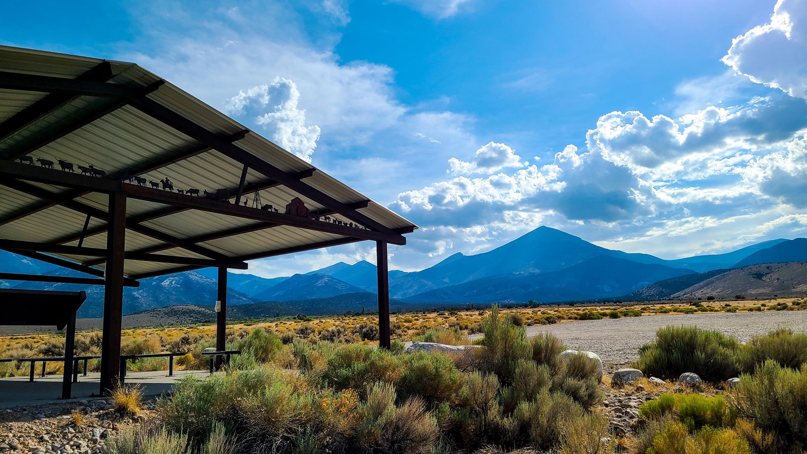 A roofed patio with signs underneath stands in sagebrush miles in front of Doso Doyabi