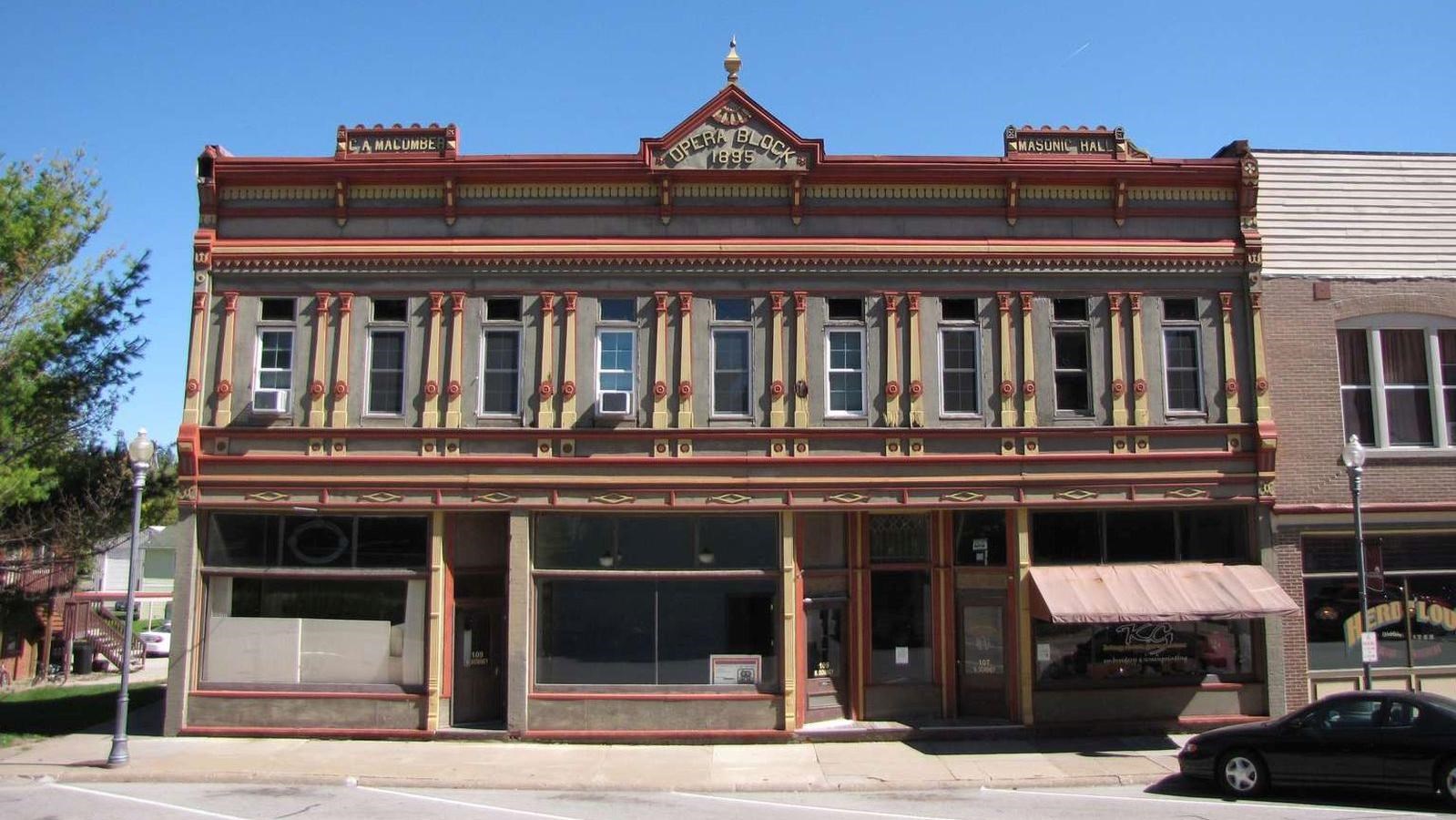 A broad two-story downtown building is ornately decorated with nine windows over its storefront.