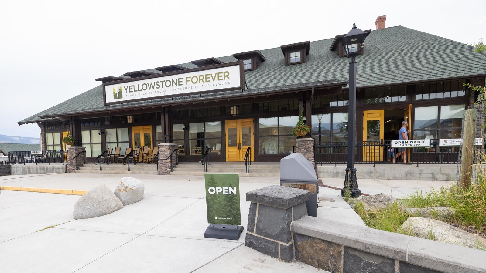 A brown retail building with windows in the front and green shingled roof.