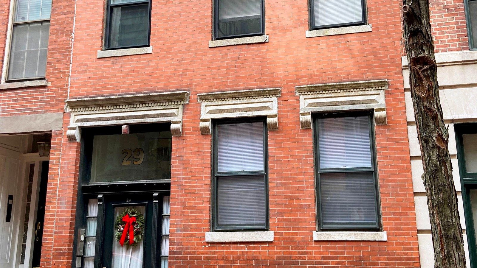 Brick residential building that is 3 portrait rectangular windows wide & more than 2 stories tall.