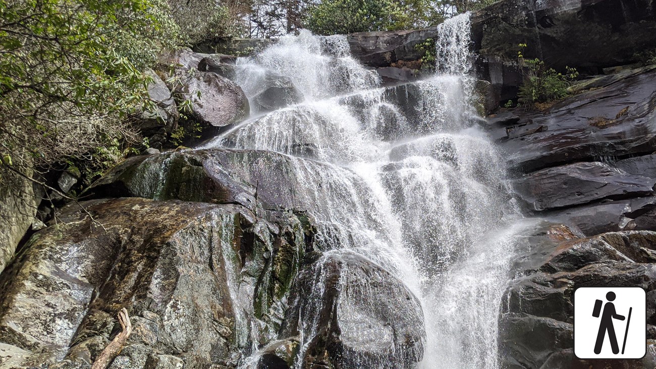 A cascading waterfall framed by large rocks and green vegetation.