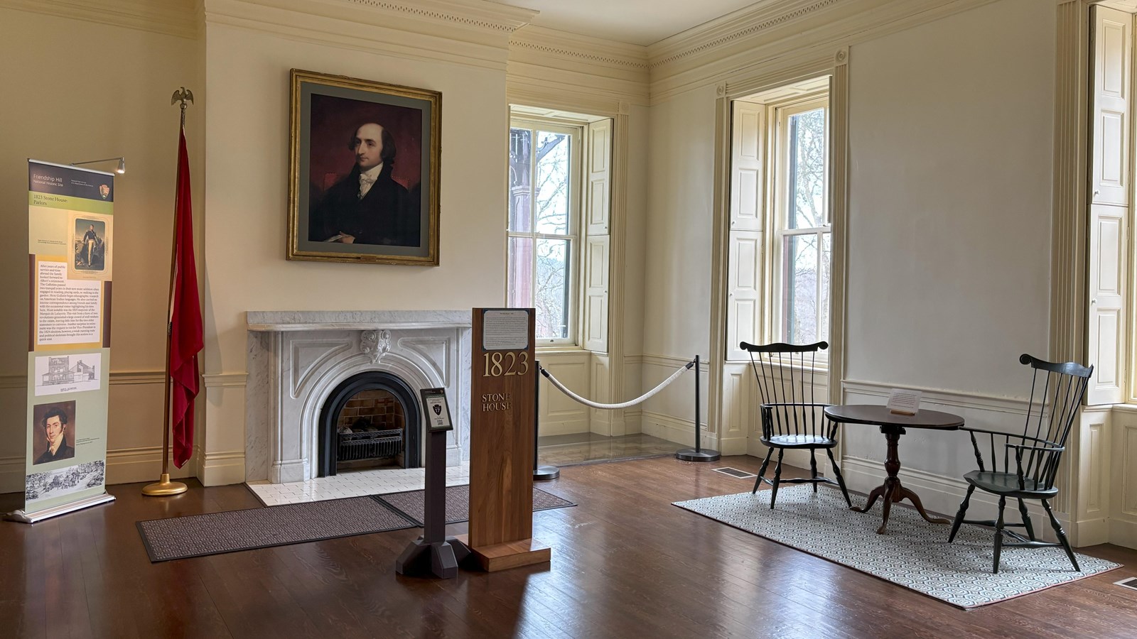 A large room with a fireplace with Gallatin\'s portrait hanging over it. 