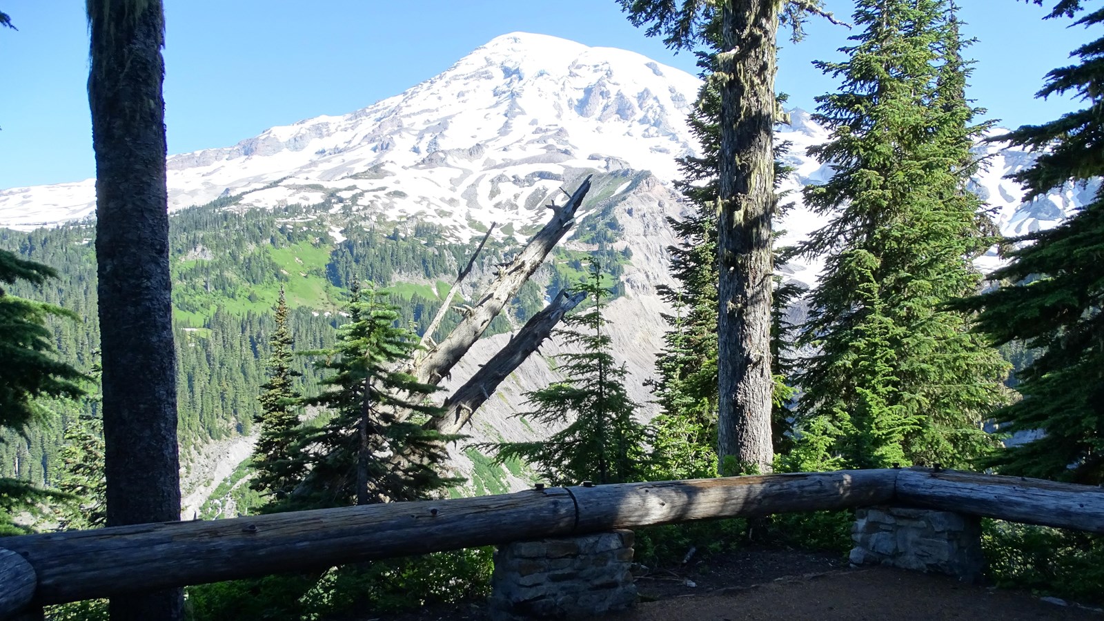 An overlook bordered on three sides by low log railings. Mount Rainier is in the distance.