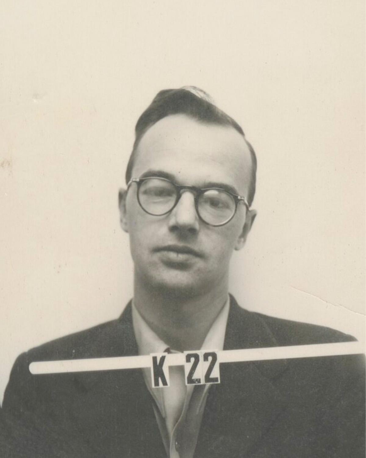 A black and white photo of a man in glasses, with ID number K22.