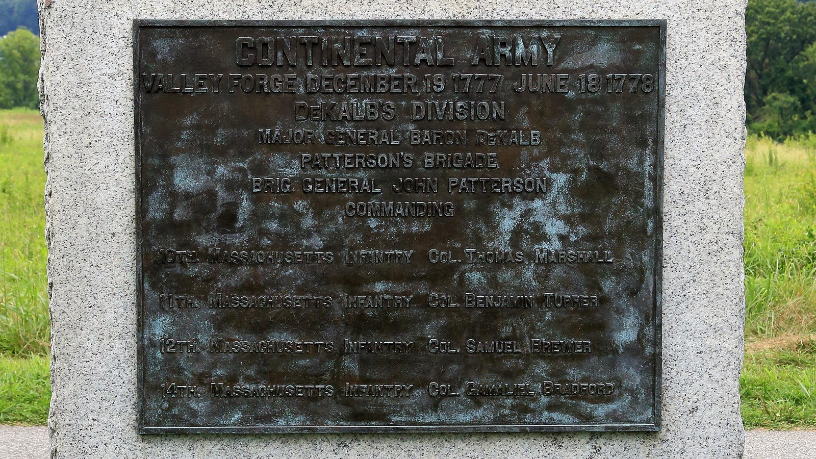 A large, smoothed granite block with a bronze plaque. Sides and bottom rough. 